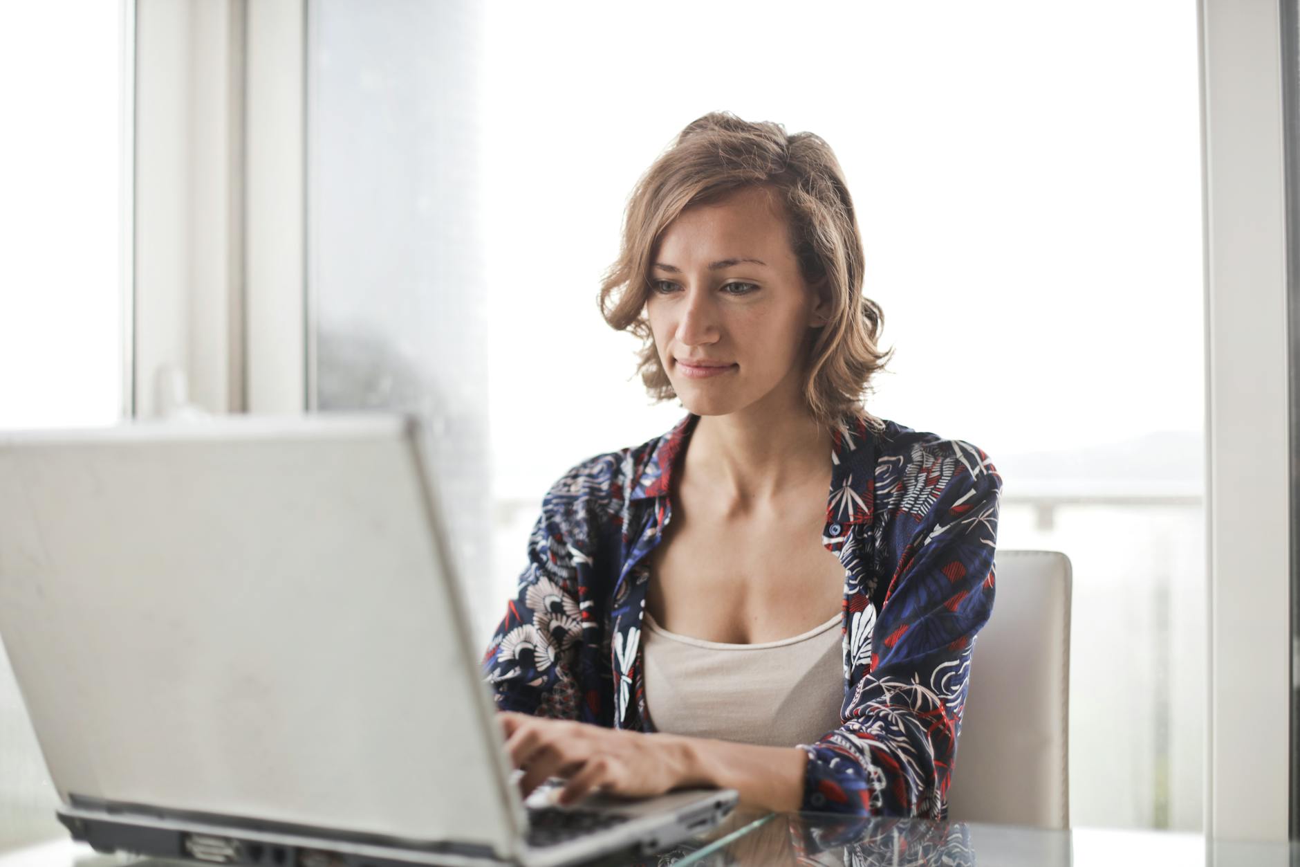 woman in blue floral top sitting while using laptop